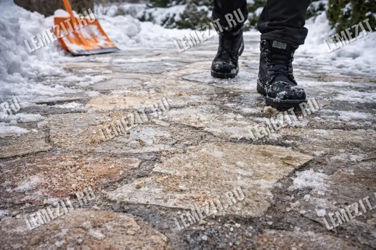 садовая дорожка из плитняка зимой с природной шероховатой поверхностью камня и снегом между плитами